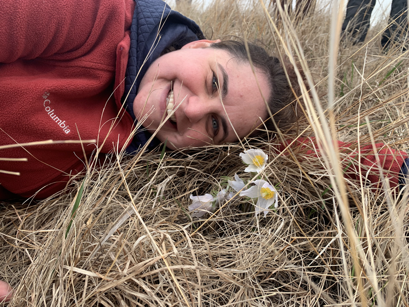 ARCS Scholar Alum Becky Barak lying in a field next to a flower ARCS Scholar Alum Becky Barak lying in a field next to a flower
